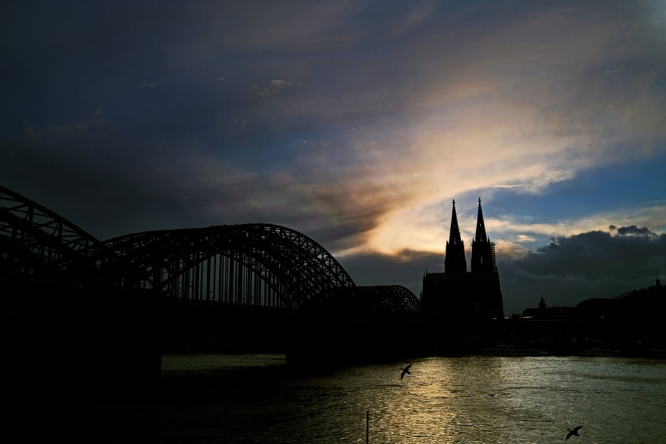 Hinter dem Dom ziehen Wolken an der Sonne vorbei. In NRW müssen sich die Menschen zum Start in die Osterferien am Wochenende auf unbeständiges Aprilwetter einstellen.