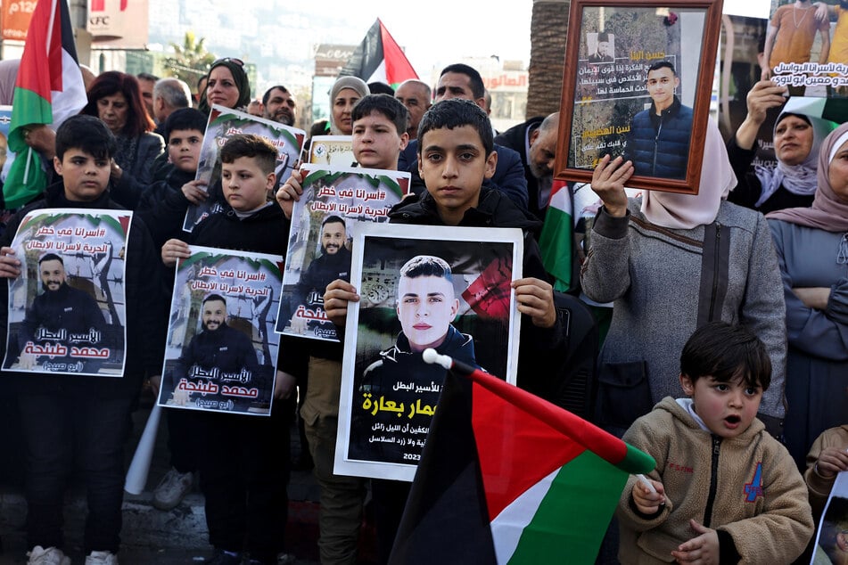 Protesters hold portraits of Palestinians held in Israelis jails during a rally in their support, in the occupied West Bank city of Nablus on December 26, 2023.