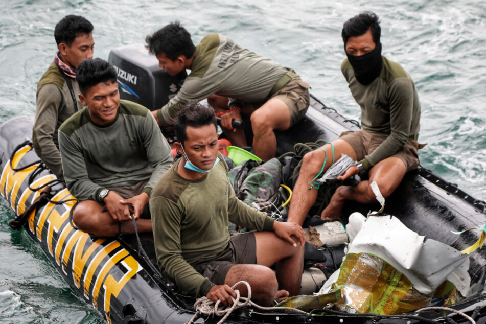 Taucher der indonesischen Marine transportieren während einer Suchaktion Flugzeugteile, die aus dem Meer geborgen wurden.