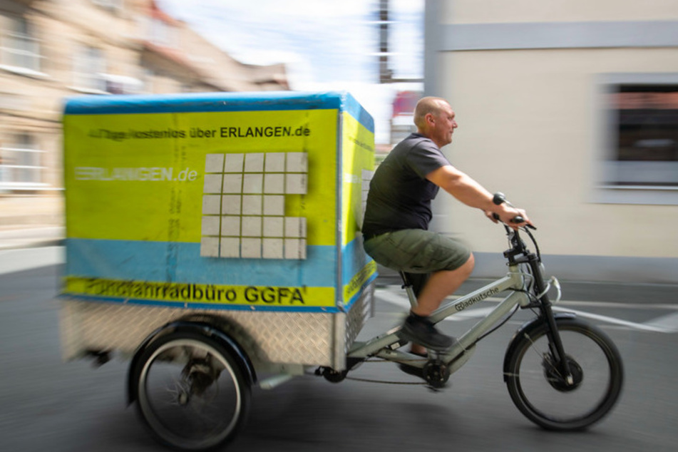 Andreas Reisch vom Cafe Hergricht, ein Verleih für Transporträder, fährt auf einem E-Lastenrad auf der Straße.