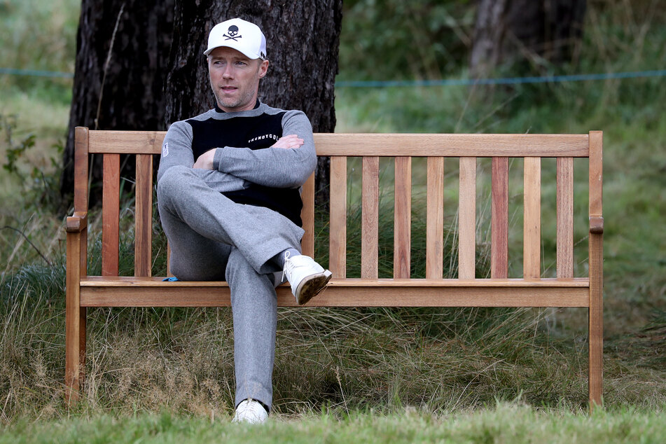 Ronan Keating, Golfer und Popsänger aus Irland, wartet auf einer Bank.