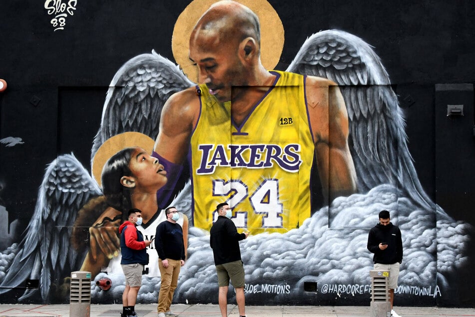 Fans pause beside a mural of Kobe Bryant (†41) and his daughter Gianna (†13) in Downtown LA.