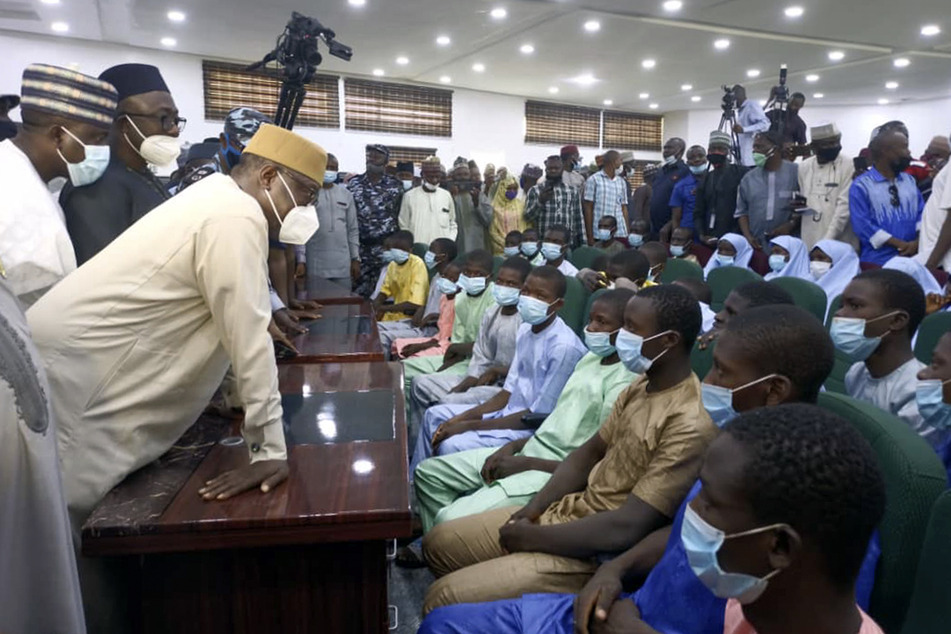 Schüler und Lehrer, die vor zwei Wochen von Angreifern aus dem Government Science College Kagara entführt wurden, sitzen nach ihrer Freilassung bei einem Treffen mit dem Gouverneur des Bundesstaates Abubakar Sani Bello (l). Sie wurden einen Tag später freigelassen, nachdem die Polizei bekannt gab, dass Bewaffnete mehr als 300 Mädchen am 26. Februar im Bundesstaat Zamfara entführt hatten.