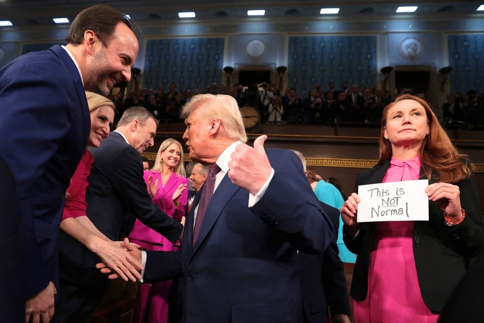 During President Donald Trump's address to Congress on Tuesday, Republican Rep. Lance Gooden of Texas (l.) ripped a protest sign from the hands of his Democratic colleague, Melanie Stansbury.