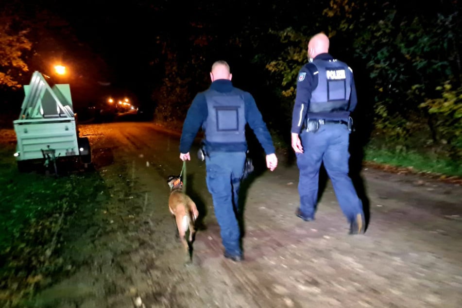 Polizisten suchen mit einem Fährtenhund die Umgebung ab.