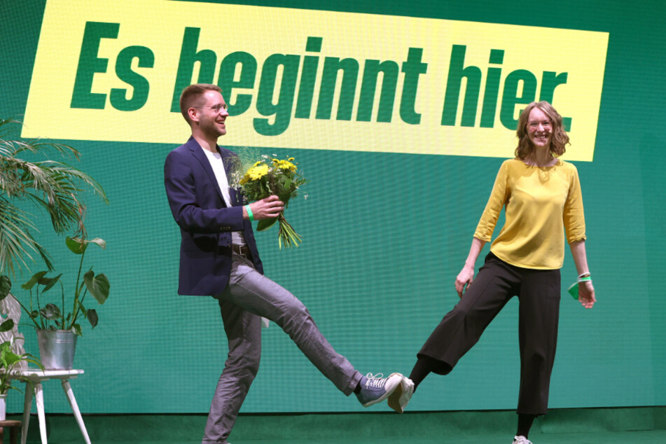 Thomas von Sarnowski (33), neu gewählter Landesvorsitzender Bündnis 90/Die Grünen Bayern, steht nach seiner Wahl neben Eva Lettenbauer (28), ebenso Landesvorsitzende der bayerischen Grünen, mit Blumen auf der Bühne.
