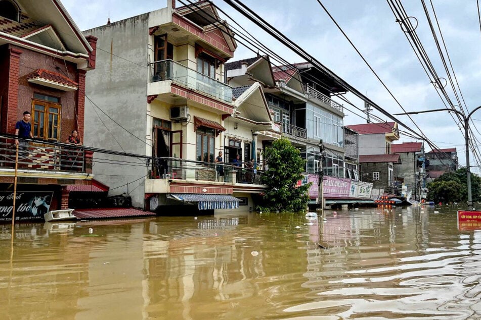 Menschen stehen auf ihren Balkonen über einer überfluteten Straße im Bezirk Trang Dinh in der Provinz Lang Son.