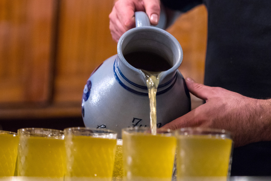 Ein Apfelwein-Glas (Geripptes) wird im Traditionslokal "Gemaltes Haus" mit einem Krug (Bembel) gefüllt.