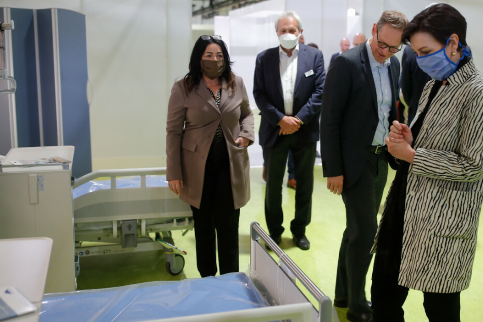 Dilek Kalayci (SPD, l), Gesundheitssenatorin von Berlin, Michael Müller (SPD, 2.v.r), Berlins Regierender Bürgermeister, und Andrea Grebe (r), Vorsitzende der Vivantes-Geschäftsführung, stehen im Corona-Behandlungszentrum in der Jaffestraße auf einer Station an einem Bett.