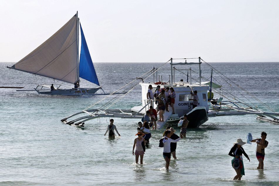 Eine Gruppe von Touristen steigt am Strand von Boracay aus einem Boot. Die Philippinen werden schon bald wieder ihre Grenzen für den internationalen Tourismus öffnen.
