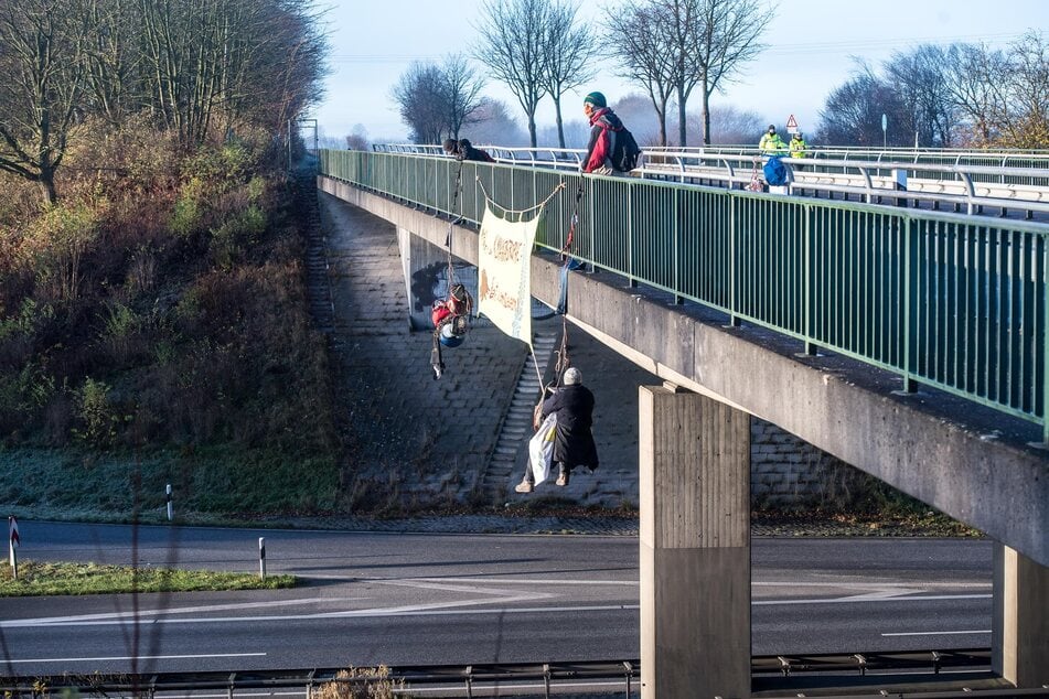 Umweltaktivisten seilen sich bei Schleswig an einer Brücke über der Autobahn 7 ab.