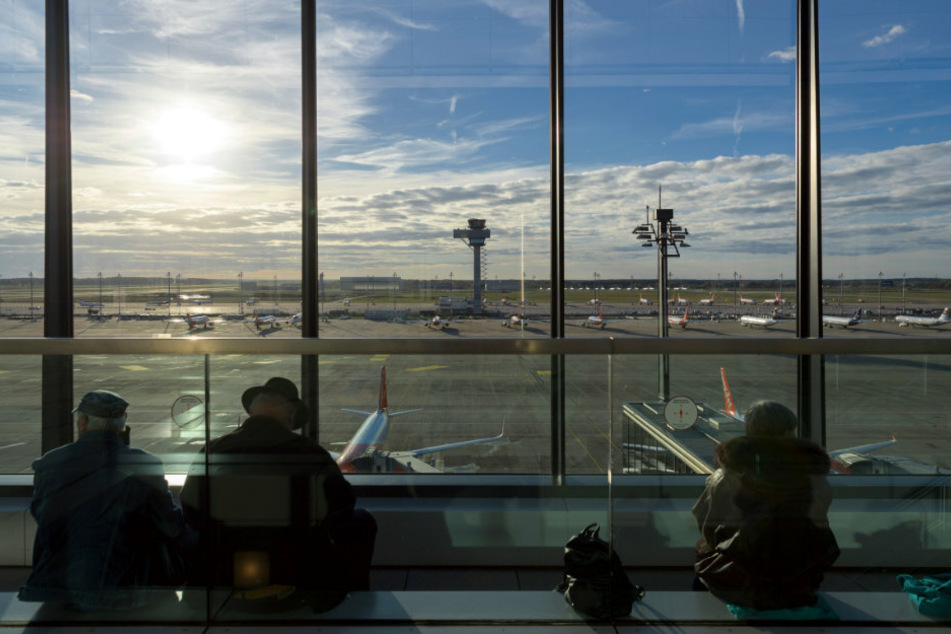 Gäste blicken von der Besucherterrasse vom Terminal 1 des Flughafens Berlin Brandenburg (BER) im Licht der untergehenden Sonne auf das Vorfeld.