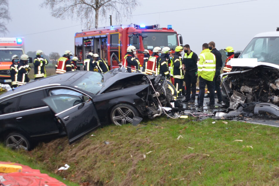 Einsatzkräfte stehen am Unfallort auf der Landstraße.