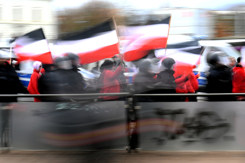 Teilnehmer einer Neonazi-Demonstration mit Reichsflaggen werden von der Polizei begleitet.