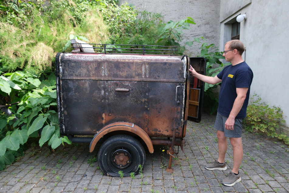 Feuerwehrmann Christian Rothe steht vor dem verbrannten Schlauchwagen, der beim verheerenden Waldbrand 2022 im Forst zurückgelassen werden musste.