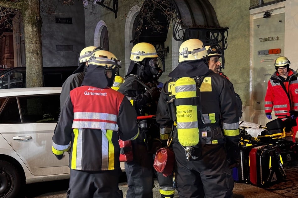 Einsatzkräfte der Feuerwehr bei einer Besprechung vor der Unterkunft im Nürnberger Stadtteil Sündersbühl.