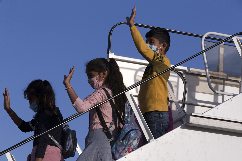 Flüchtlinge aus Griechenland winken in Athen, bevor sie ins Flugzeug nach Deutschland steigen.