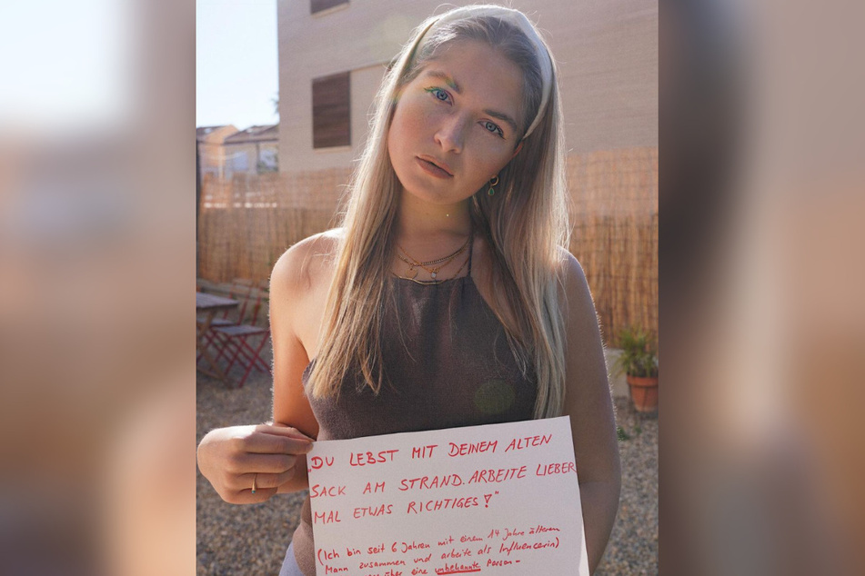 Die 28-Jährige hält ein Schild, auf dem einer der unzähligen Hasskommentare steht, die sie geschickt bekommt.