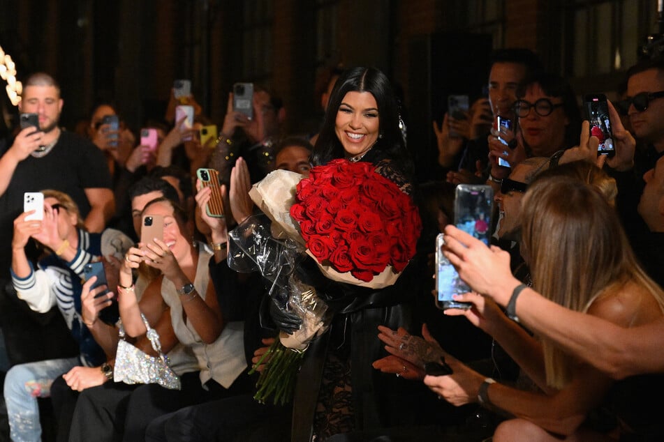 Kourtney Kardashian receives roses from her husband Travis Barker at the Boohoo by Kourtney Kardashian show during New York Fashion Week.