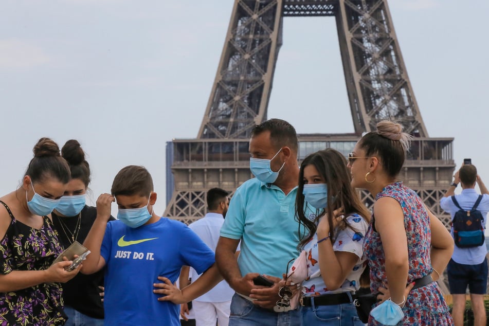 Eine italienische Familie trägt Mundschutze und steht auf dem Palais du Trocadéro mit Blick auf den Eiffelturm.