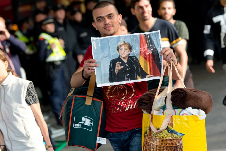 Bei seiner Ankunft im September 2015 in München hält ein Flüchtling ein Foto von Angela Merkel in den Händen.
