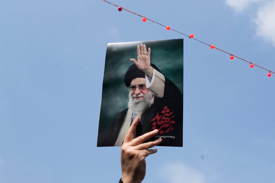 Eine Frau hält ein Poster des verstorbenen iranischen Obersten Führers Ajatollah Ali Chamenei in die Höhe, während sie an einem Trauerzug für hochrangige iranische Militärs und Zivilisten Anfang April 2026 teilnimmt.