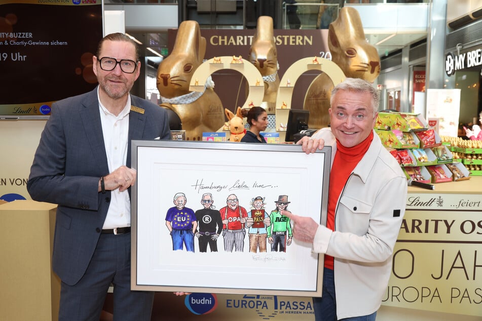 Karsten Bärschneider, Center Manager der Europa Passage, und Künstler und Comedian Jörg Knör (66) mit seinem Bild für den guten Zweck.