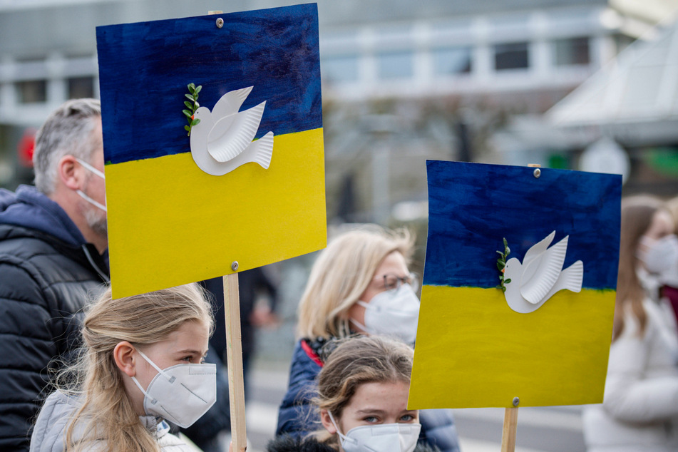 Ihre Solidarität zur Ukraine bekunden weltweit Menschen mit Plakaten, auf denen die Friedenstaube zu sehen ist.