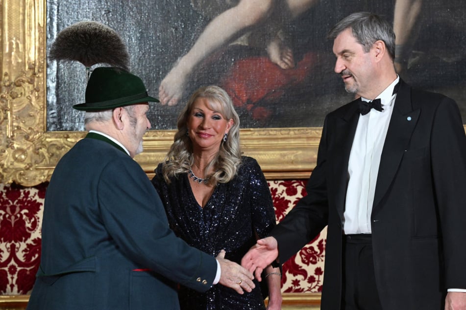 Bayerns Ministerpräsident Markus Söder (58, CSU, r.) und seine Frau Karin Baumüller-Söder (52, M.) begrüßen beim Neujahrsempfang in der Münchner Residenz verschiedene Gäste (hier den Trachtler Max Bertl).