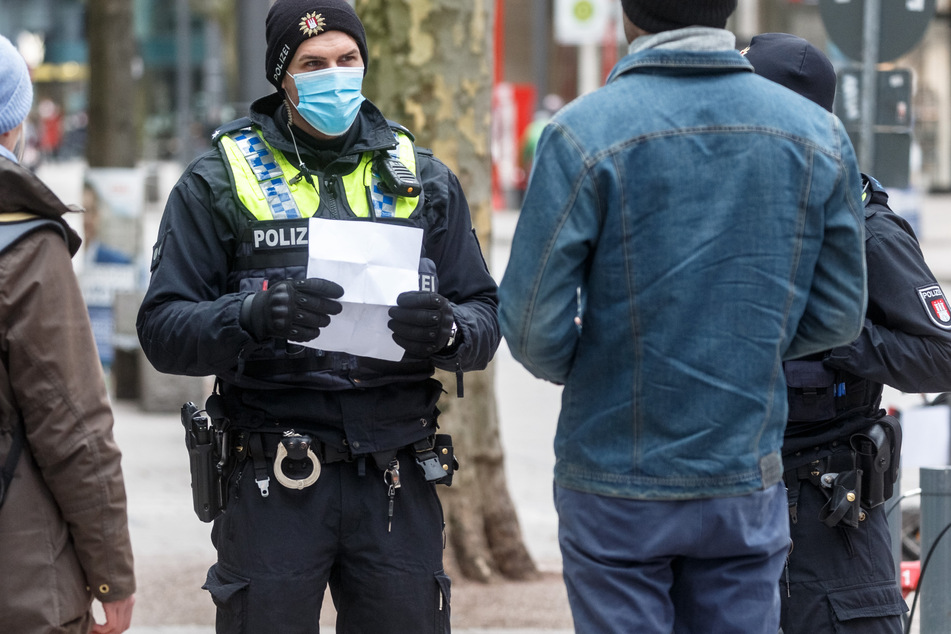 Polizisten sprechen in der Hamburger Innenstadt Passanten an, die ohne eine Mund-Nase-Bedeckung unterwegs sind. (Archivbild)