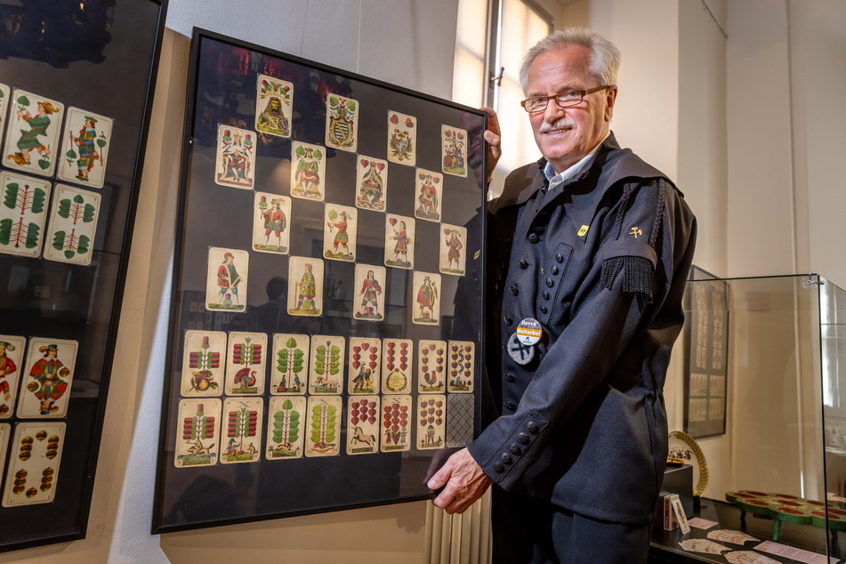 Reiner Uhlisch (76) vom Schneeberger Skat-Verein zeigt eine Tafel mit alten Spielkarten.
