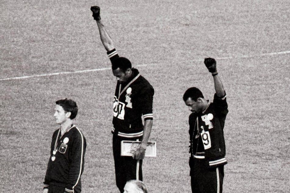 Gold and bronze medalists Tommie Smith (c) and John Carlos (r) raise their arms as a Black Power gesture during the 1968 Olympic games