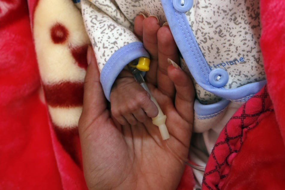 Jemen, Sanaa: Eine Frau hält das winzige Händchen ihres Babys, das auf der Station für unterernährte Kinder in einem Krankenhaus medizinisch versorgt wird.