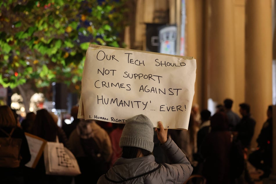 A demonstrator raises a sign reading "Our Tech Should Not Support Crimes Against Humanity... Ever!" during a protest in San Francisco, California.