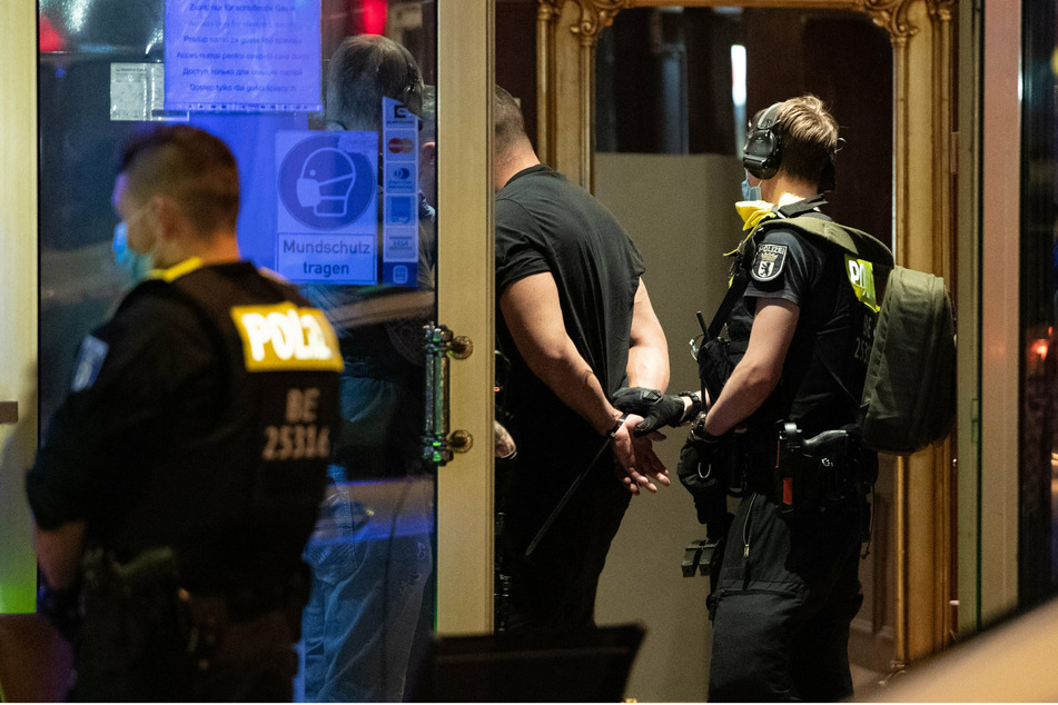 Ein Polizeibeamter hält einen gefesselten Mann im Hotel "Panorama" in der Nähe des Kurfürstendamms.