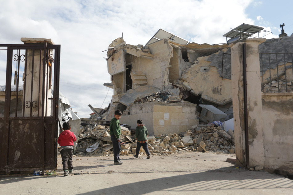 Syrian children gather next to a collapsed school in the town of Azaz on the border with Turkey following the deadly earthquake.