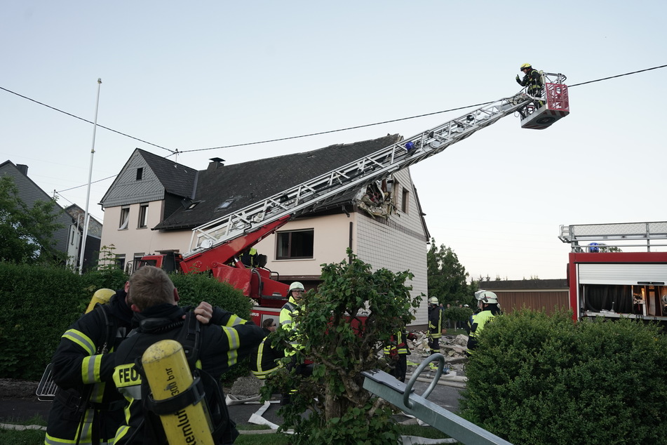 Feuerwehrleute sichern ein Wohnhaus, nachdem ein Kleinflugzeug am Samstag in das Dach gestürzt ist.