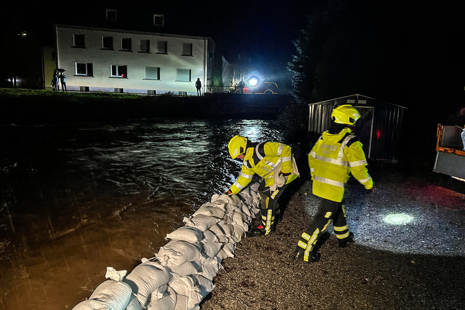 Einsatzkräfte der Feuerwehr bauen einen Damm aus Sandsäcken zum Schutz vor dem Hochwasser der Volme.