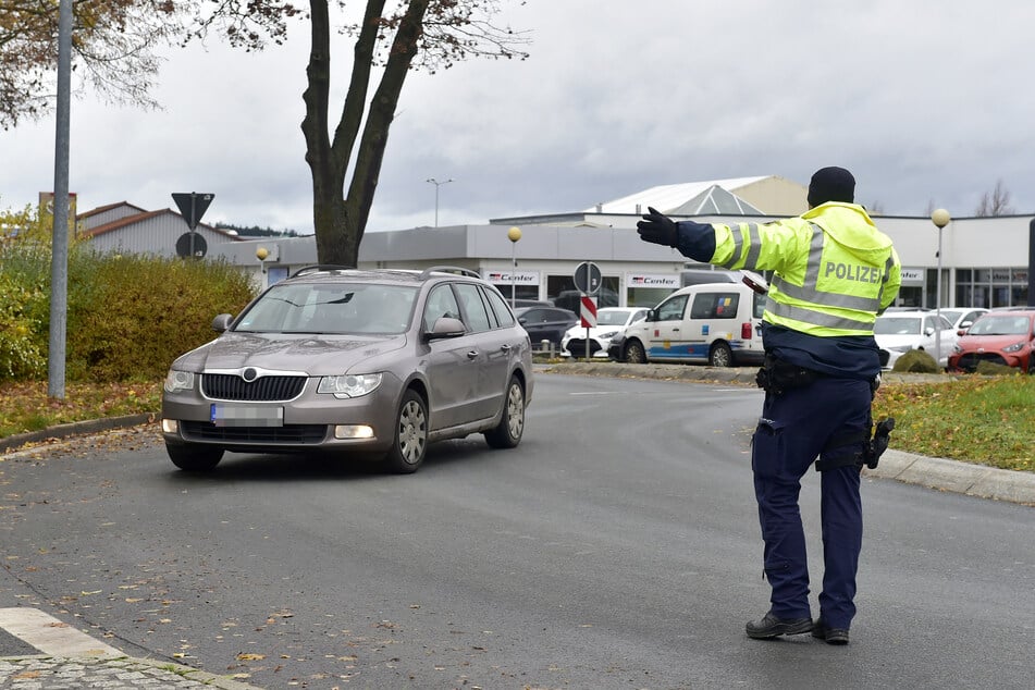 Ein Polizist leitet ein Auto aus dem Verkehr zur Kontrolle.