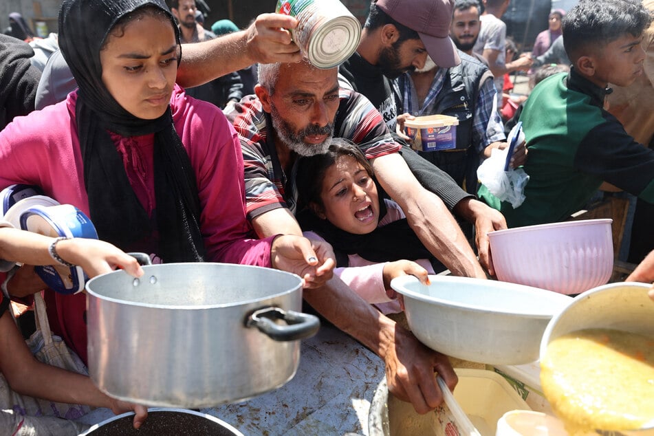 Palestinians line up for a hot meal at a charity kitchen at the Nuseirat refugee camp in the central Gaza Strip on May 4, 2025.