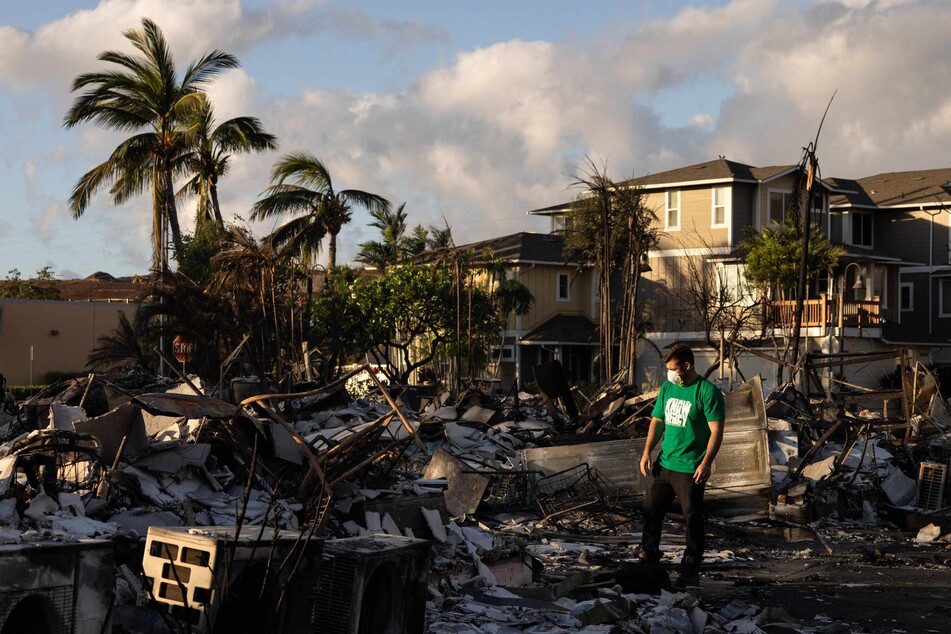 A volunteer makes wades through a charred apartment complex in the aftermath of a wildfire in Lahaina, in western Maui, Hawaii.