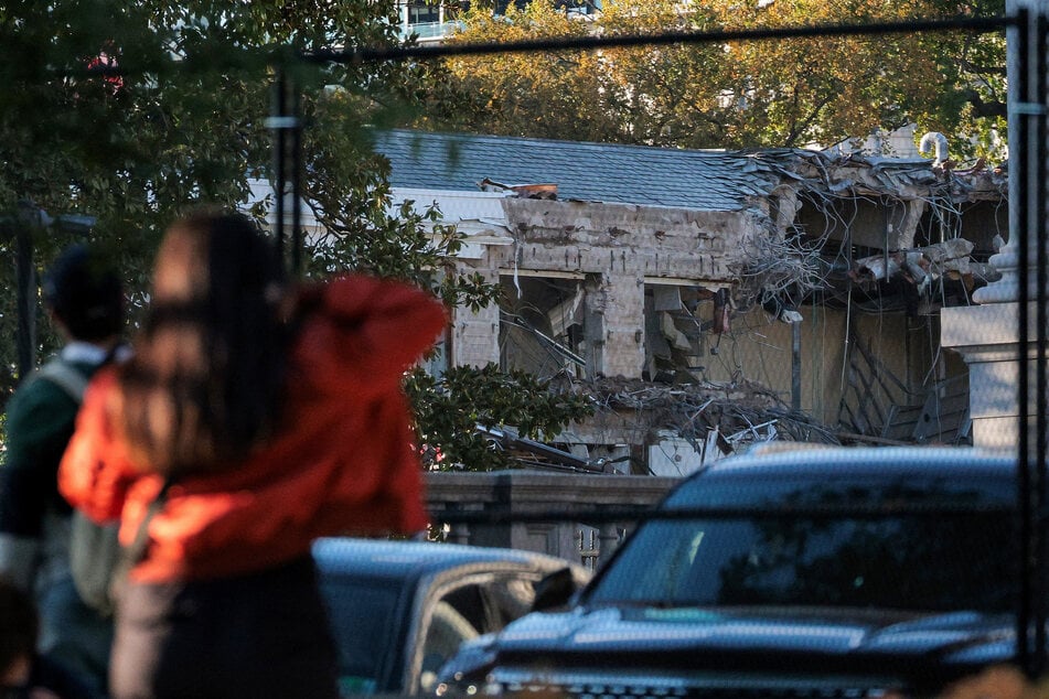 People watch as work crews demolish the facade of the East Wing of the White House on October 20, 2025.