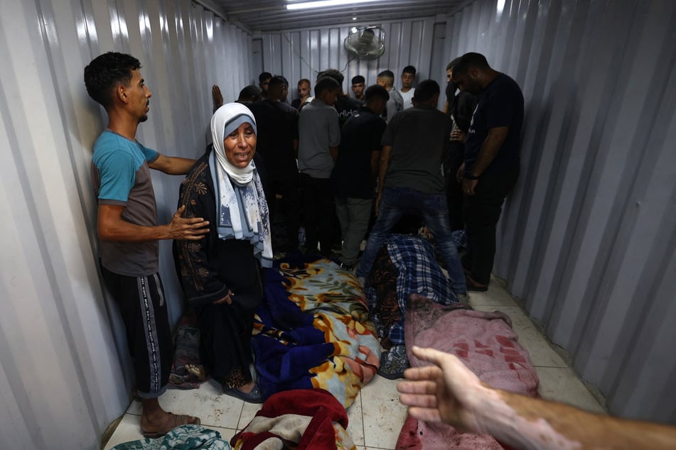 Palestinians gather around the bodies of people killed in an Israeli strike near the Nuseirat refugee camp, at the morgue in the al-Awda Hospital in the central Gaza Strip, on September 24, 2025.