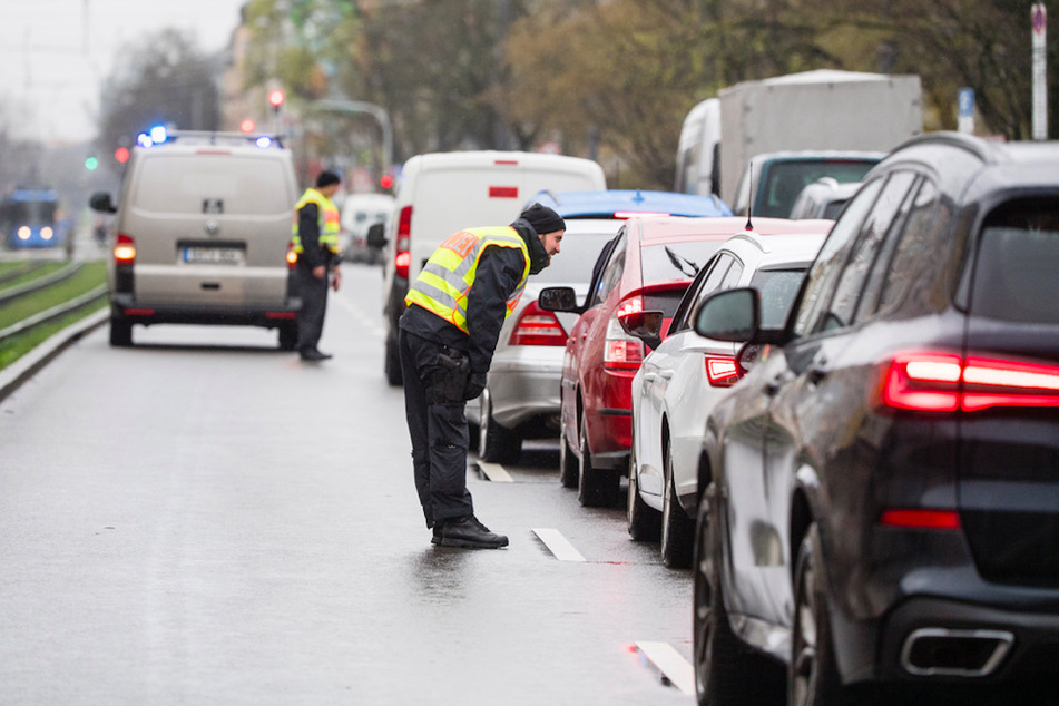 Ein Polizist befragt an einer Kontrollstelle den Fahrer eines Autos in München.