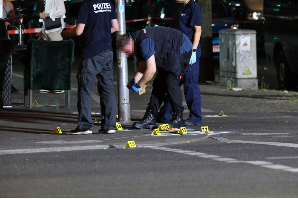 Ein Polizist stellt vor dem Lokal in Berlin-Wedding Patronenhülsen sicher.