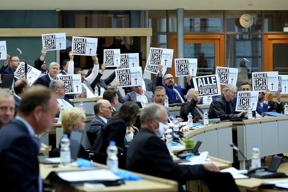 Abgeordnete der AfD-Fraktion halten zu Beginn der Landtagssitzung Schilder in die Höhe.