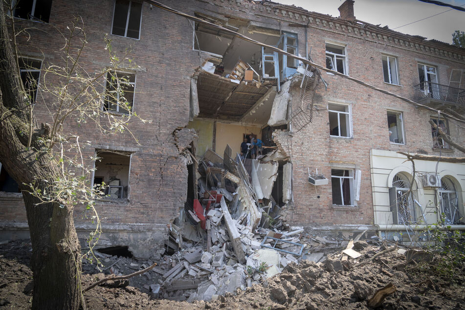 Menschen bergen einige ihrer Habseligkeiten aus einem Gebäude, das bei einem russischen Raketenangriff im Stadtzentrum von Bachmut beschädigt wurde.