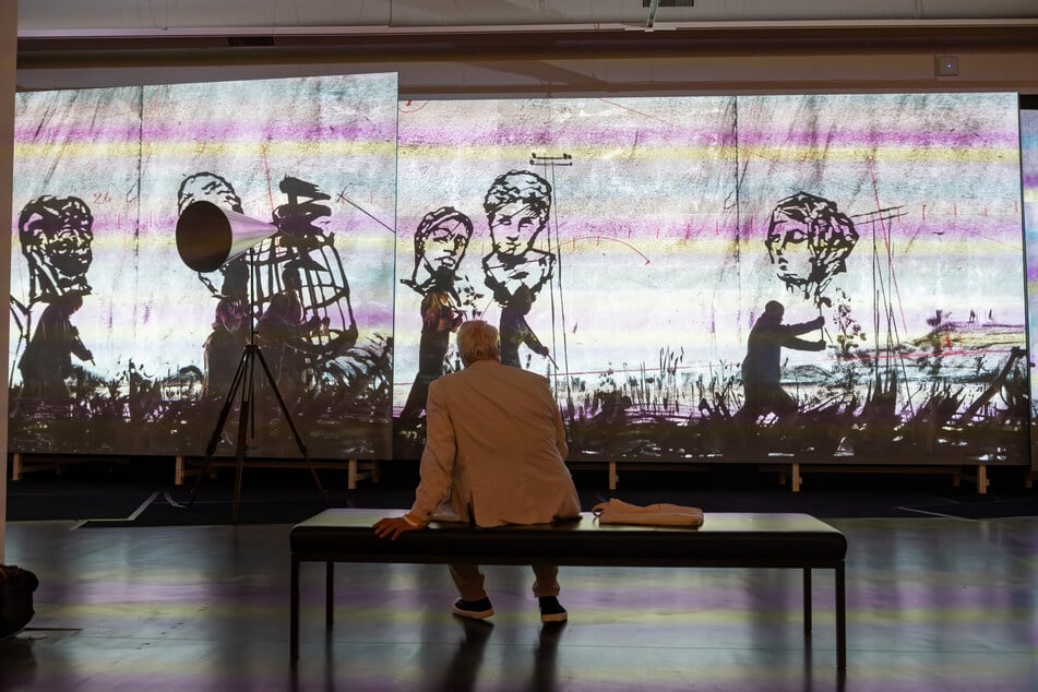 Ein Besucher betrachtet die Prozession "More Sweetly Play the Dance."