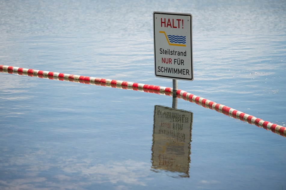 Ein Schild mit der Aufschrift "Halt Steilstrand nur für Schwimmer" steckt in einem See. (Symbolbild)