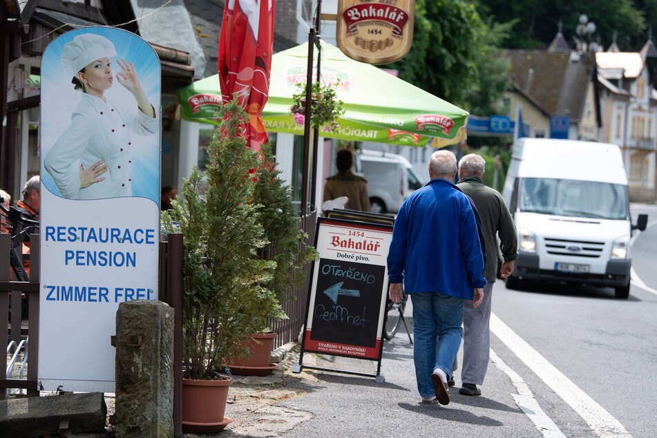 Passanten gehen auf einer Straße nahe der deutsch/tschechischen Grenze an einem Restaurant vorbei.